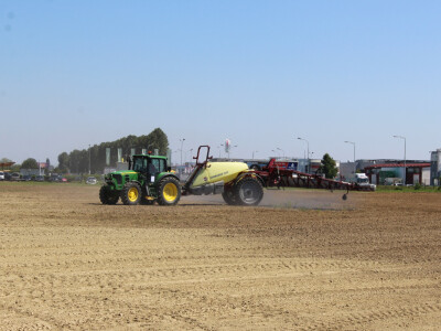 Traktor JohnDeere + vučena prskalica u polju Traktor JohnDeere + vučena prskalica u polju