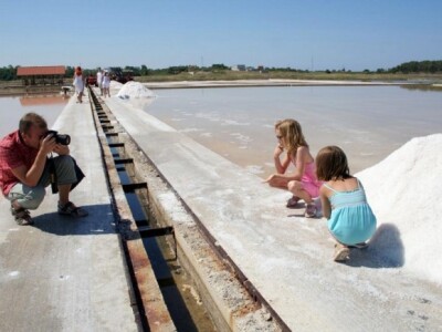 Turistički motiv - djeca i turisti uz bazene i hrpe čiste soli u stonskoj Solani